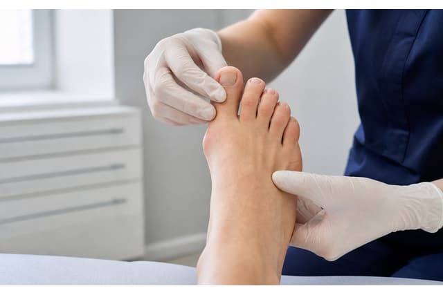 Un praticien examine la base du gros orteil d'un patient