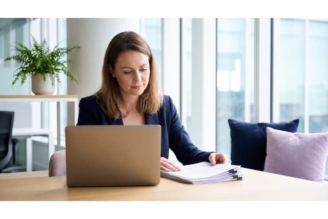 Practice administrator reviewing records at a laptop